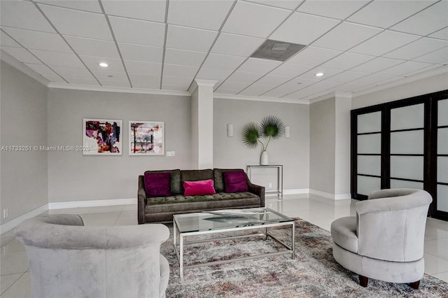 living room featuring a drop ceiling, ornamental molding, and light tile patterned flooring