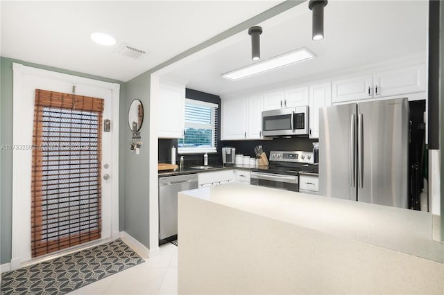 kitchen featuring white cabinetry, sink, light tile patterned flooring, and appliances with stainless steel finishes