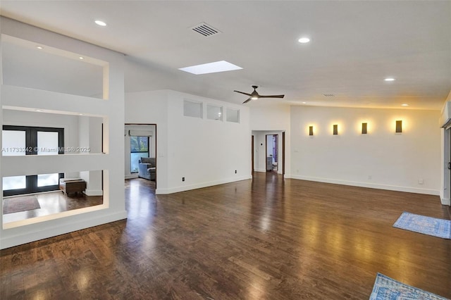 unfurnished living room with dark wood-type flooring, lofted ceiling with skylight, and ceiling fan