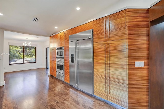 kitchen with stainless steel appliances, dark wood-type flooring, a chandelier, and decorative light fixtures