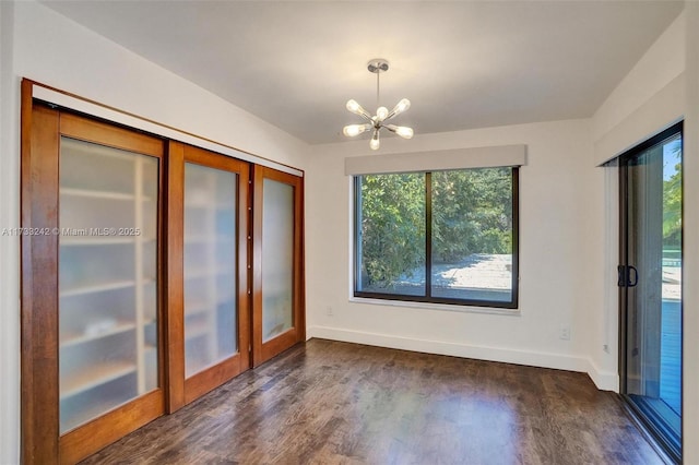 unfurnished dining area featuring a chandelier, dark hardwood / wood-style flooring, and french doors