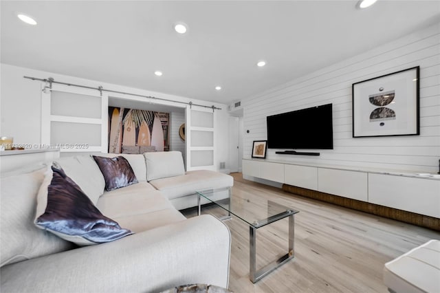 living room featuring a barn door and light wood-type flooring