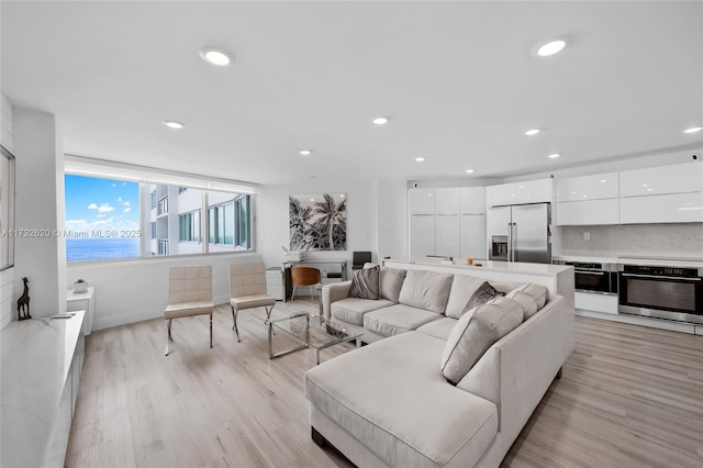 living room with light hardwood / wood-style floors and a water view