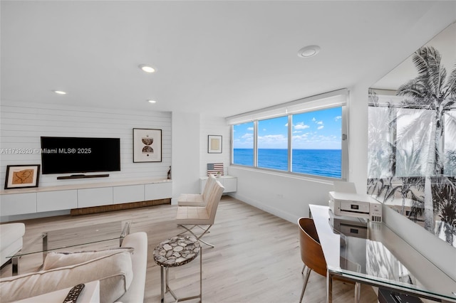 living room featuring light hardwood / wood-style flooring and a water view