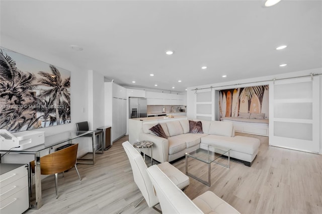 living room with a barn door and light hardwood / wood-style floors