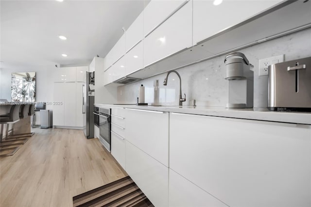 kitchen with white cabinetry, appliances with stainless steel finishes, and light hardwood / wood-style floors