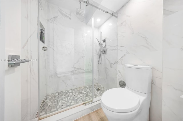 bathroom with hardwood / wood-style flooring, toilet, and a shower with shower door