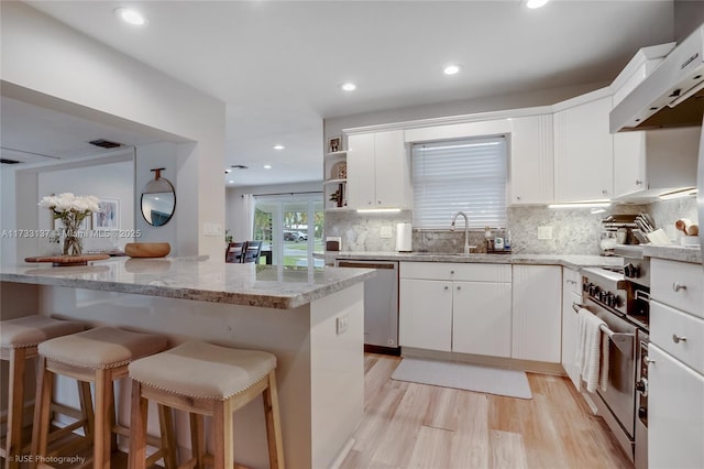 kitchen featuring appliances with stainless steel finishes, sink, wall chimney range hood, and white cabinets