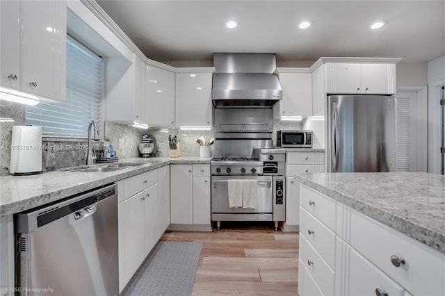 kitchen featuring sink, white cabinets, light hardwood / wood-style floors, stainless steel appliances, and wall chimney range hood