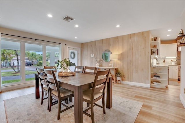 dining area featuring light hardwood / wood-style floors and wood walls