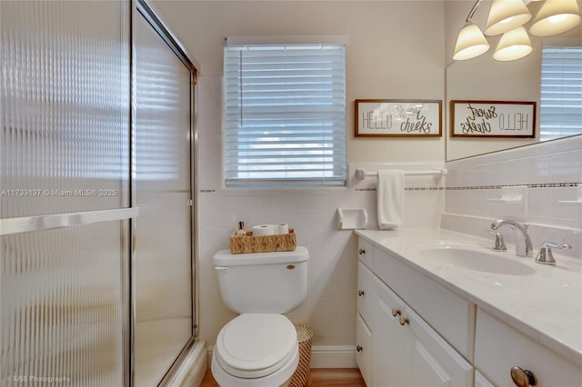 bathroom featuring vanity, a shower with door, tile walls, and toilet