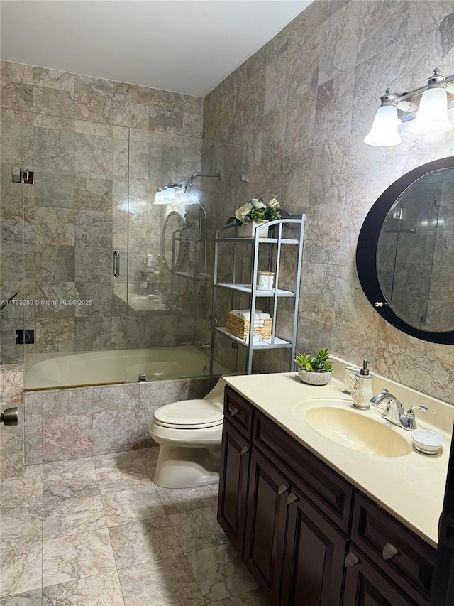 full bathroom with bath / shower combo with glass door, tile walls, vanity, and toilet