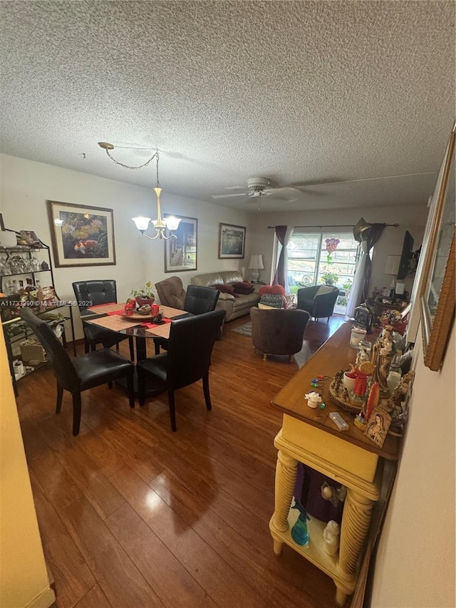 dining area featuring hardwood / wood-style floors, ceiling fan with notable chandelier, and a textured ceiling