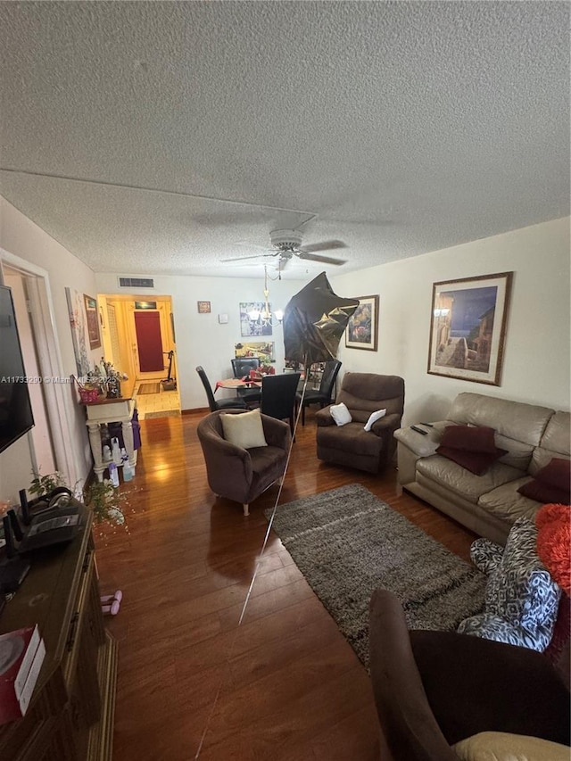 living room with ceiling fan, dark hardwood / wood-style floors, and a textured ceiling