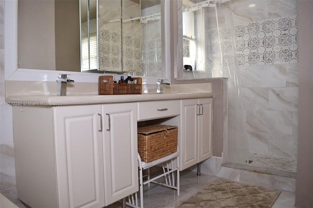 bathroom featuring vanity, a tile shower, and tile patterned floors