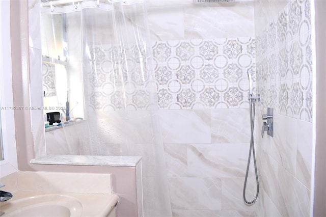 bathroom with tiled shower and sink