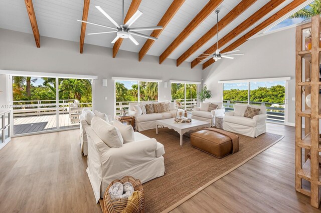 living room featuring beamed ceiling, a ceiling fan, light wood finished floors, and high vaulted ceiling