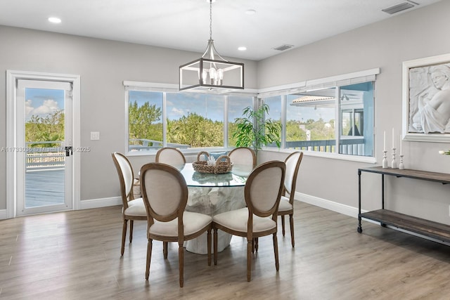 dining space with baseboards, a notable chandelier, wood finished floors, and visible vents