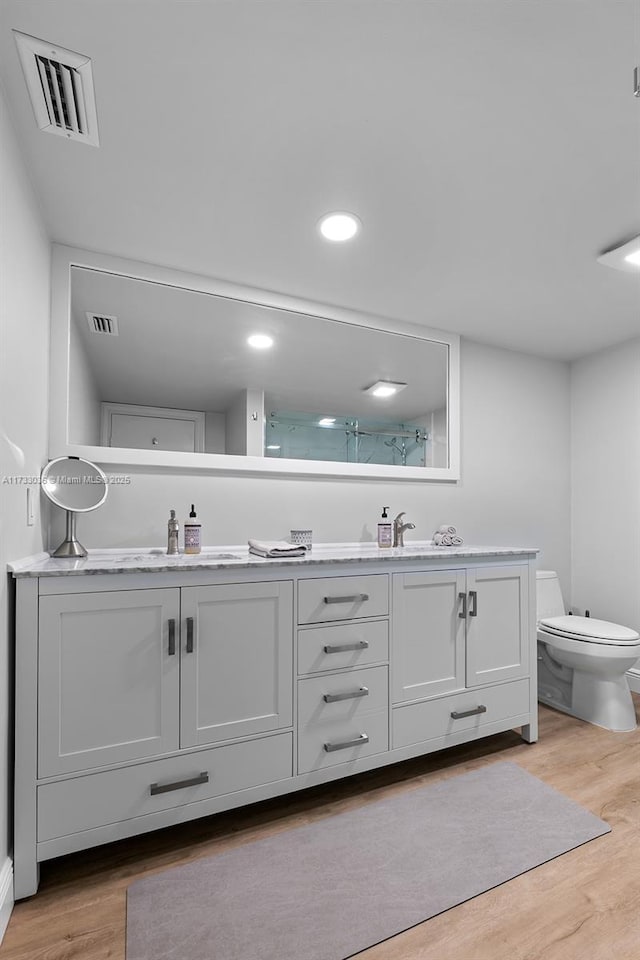 bathroom with double vanity, wood finished floors, visible vents, and a sink