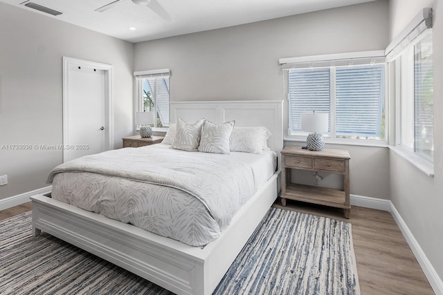 bedroom with wood finished floors, visible vents, a ceiling fan, and baseboards