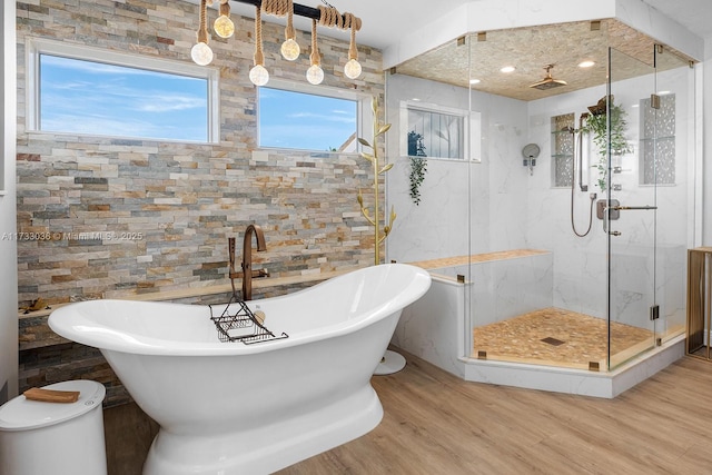full bath featuring a freestanding tub, wood finished floors, and a marble finish shower