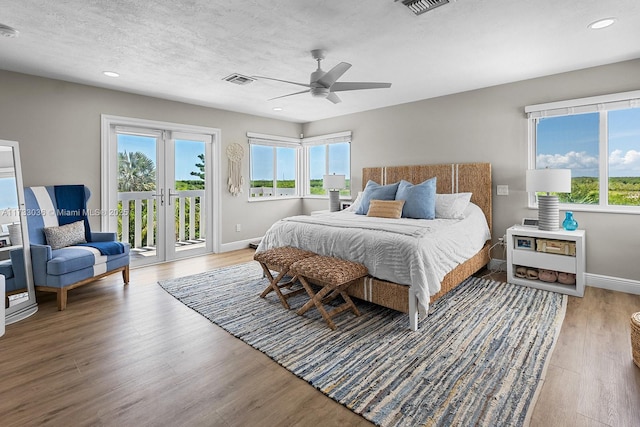 bedroom with multiple windows, baseboards, wood finished floors, and access to exterior