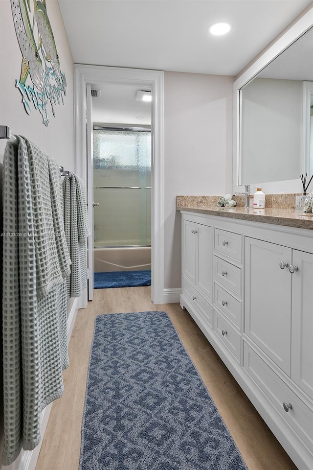full bath with baseboards, vanity, wood finished floors, and combined bath / shower with glass door
