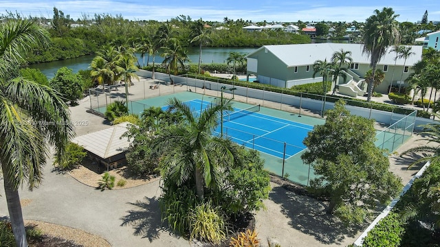 view of tennis court featuring fence and a water view