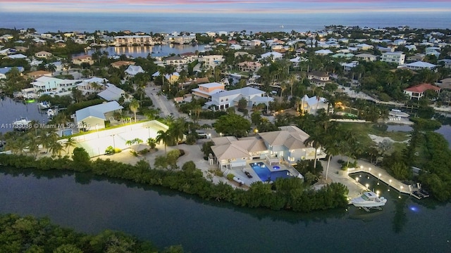 aerial view at dusk featuring a water view and a residential view