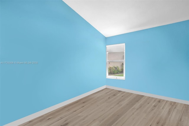 empty room featuring vaulted ceiling and light wood-type flooring