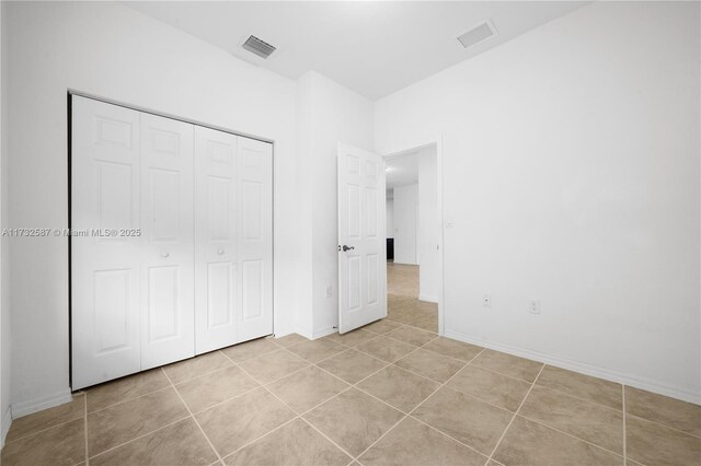 unfurnished bedroom with light tile patterned flooring and a closet