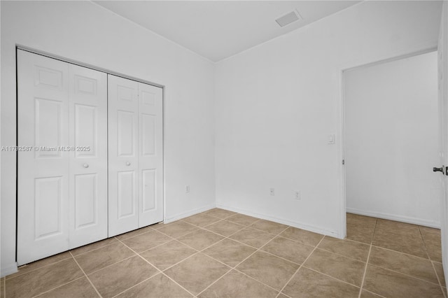 unfurnished bedroom with light tile patterned floors and a closet