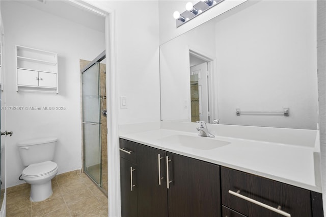 bathroom featuring tile patterned floors, vanity, toilet, and a shower with door