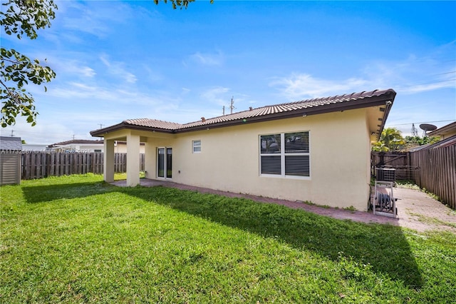 rear view of property with a yard and central AC