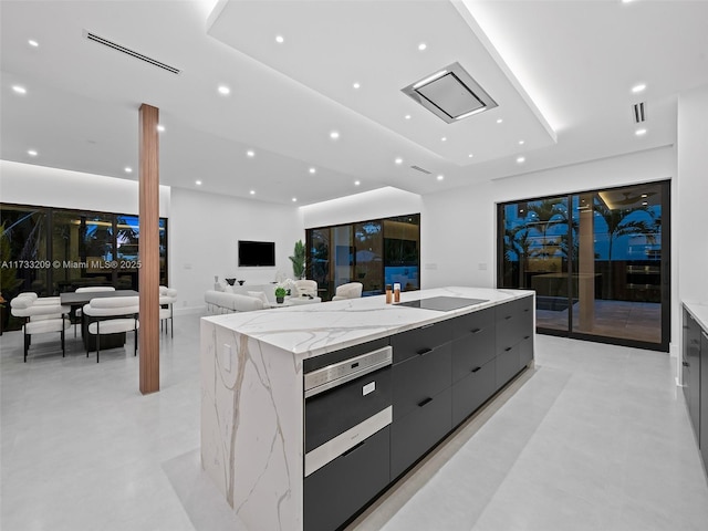 kitchen featuring black electric cooktop, light stone counters, wall oven, and a spacious island