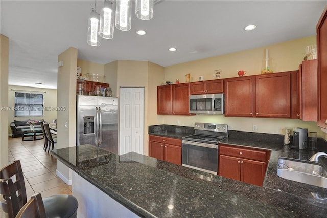 kitchen with light tile patterned flooring, sink, decorative light fixtures, dark stone countertops, and stainless steel appliances