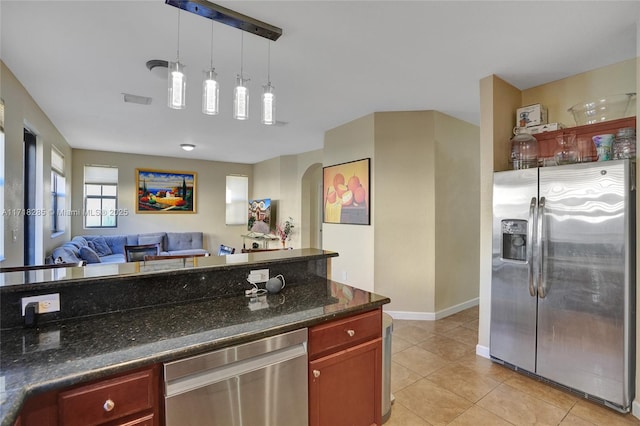 kitchen with pendant lighting, stainless steel appliances, light tile patterned flooring, and dark stone countertops