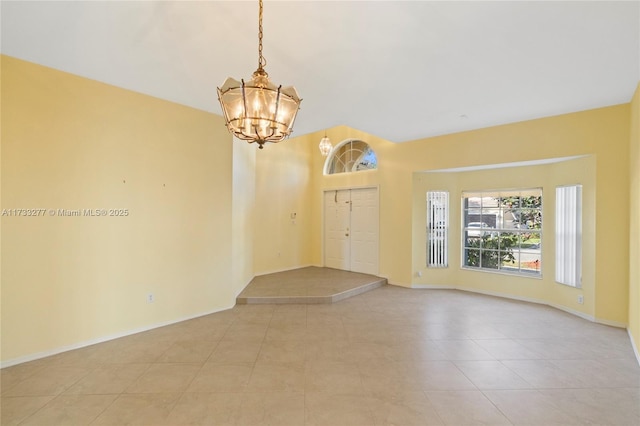 tiled empty room featuring a notable chandelier