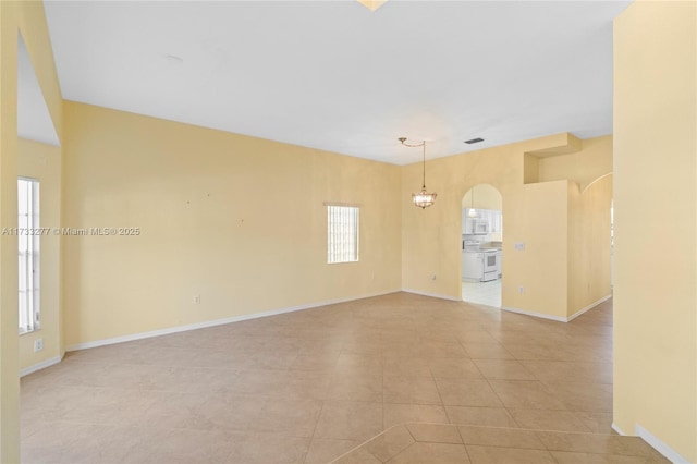 tiled empty room featuring a notable chandelier