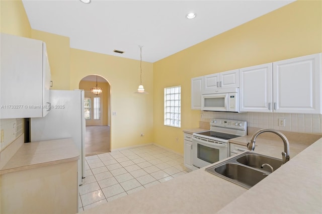 kitchen with white cabinetry, sink, hanging light fixtures, light tile patterned floors, and white appliances