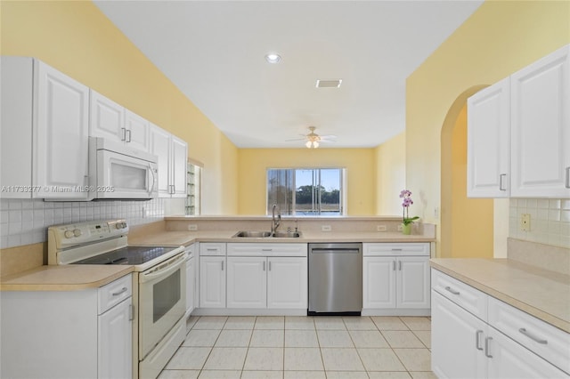 kitchen featuring sink, white appliances, backsplash, white cabinets, and light tile patterned flooring