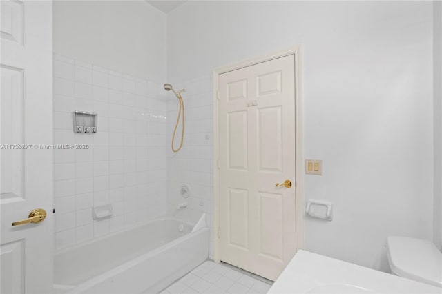 bathroom featuring tile patterned flooring, tiled shower / bath combo, and toilet