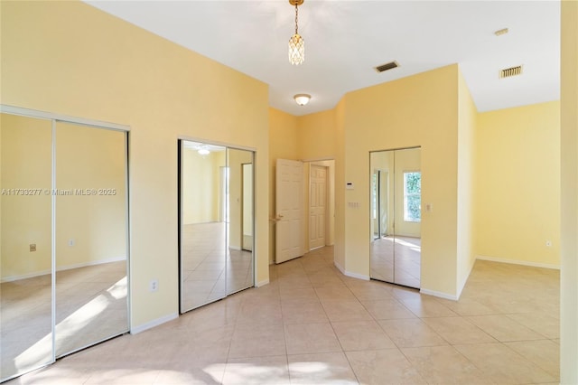 unfurnished bedroom featuring light tile patterned flooring and two closets