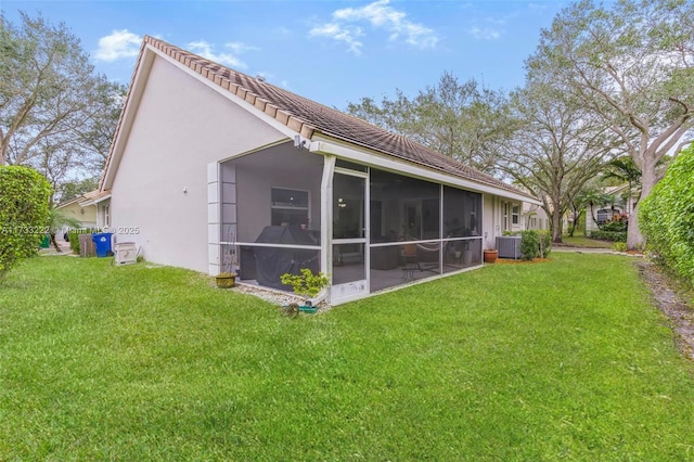 rear view of house with a sunroom, cooling unit, and a lawn