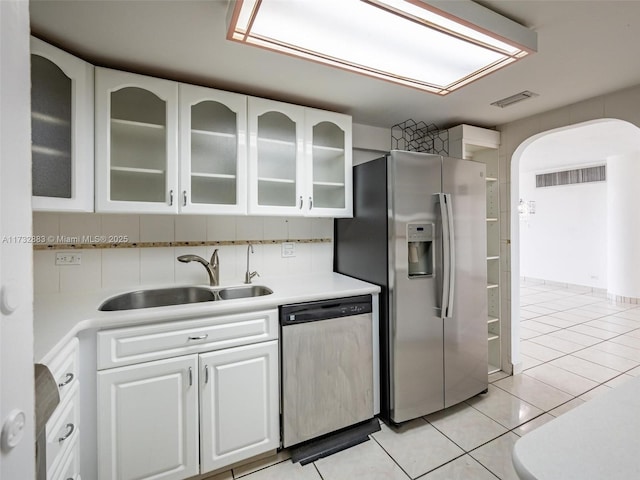 kitchen with sink, light tile patterned floors, appliances with stainless steel finishes, decorative backsplash, and white cabinets