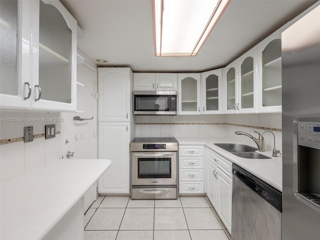 kitchen with sink, light tile patterned flooring, white cabinets, and appliances with stainless steel finishes