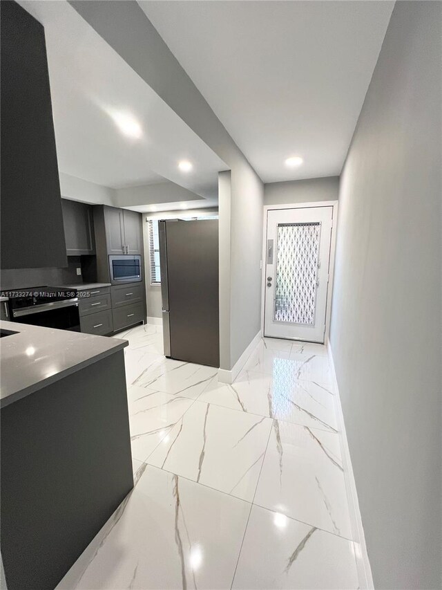 kitchen with electric stove, gray cabinets, stainless steel refrigerator, and tasteful backsplash