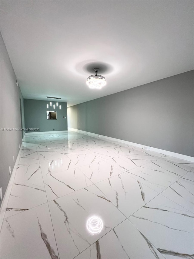 spare room with marble finish floor and baseboards