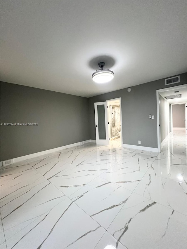 empty room featuring visible vents, marble finish floor, and baseboards