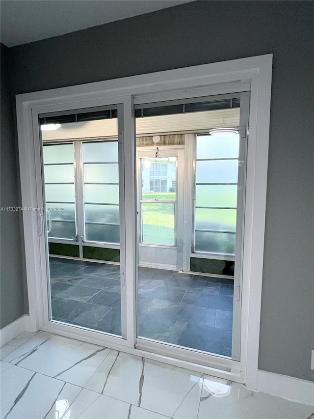 doorway to outside with marble finish floor and baseboards